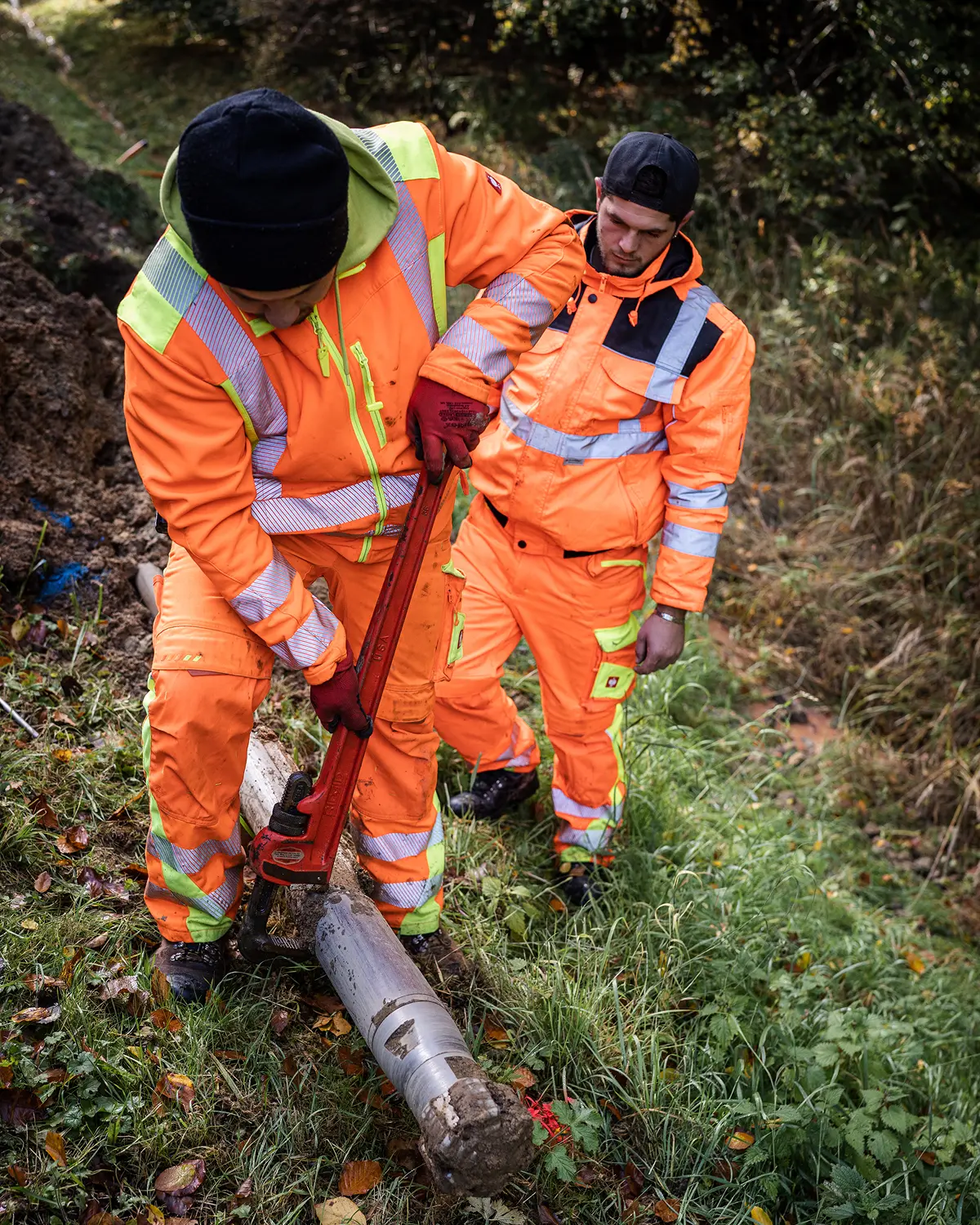 Zwei Schmabo Mitarbeiter in Warnkleidung lösen ein Bohrgestänge im Gelände